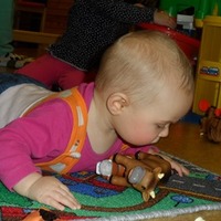 Vauva on lattialla ja tutkii lelua.