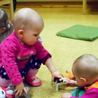 Kaksi vauvaa leikkii lattialla.