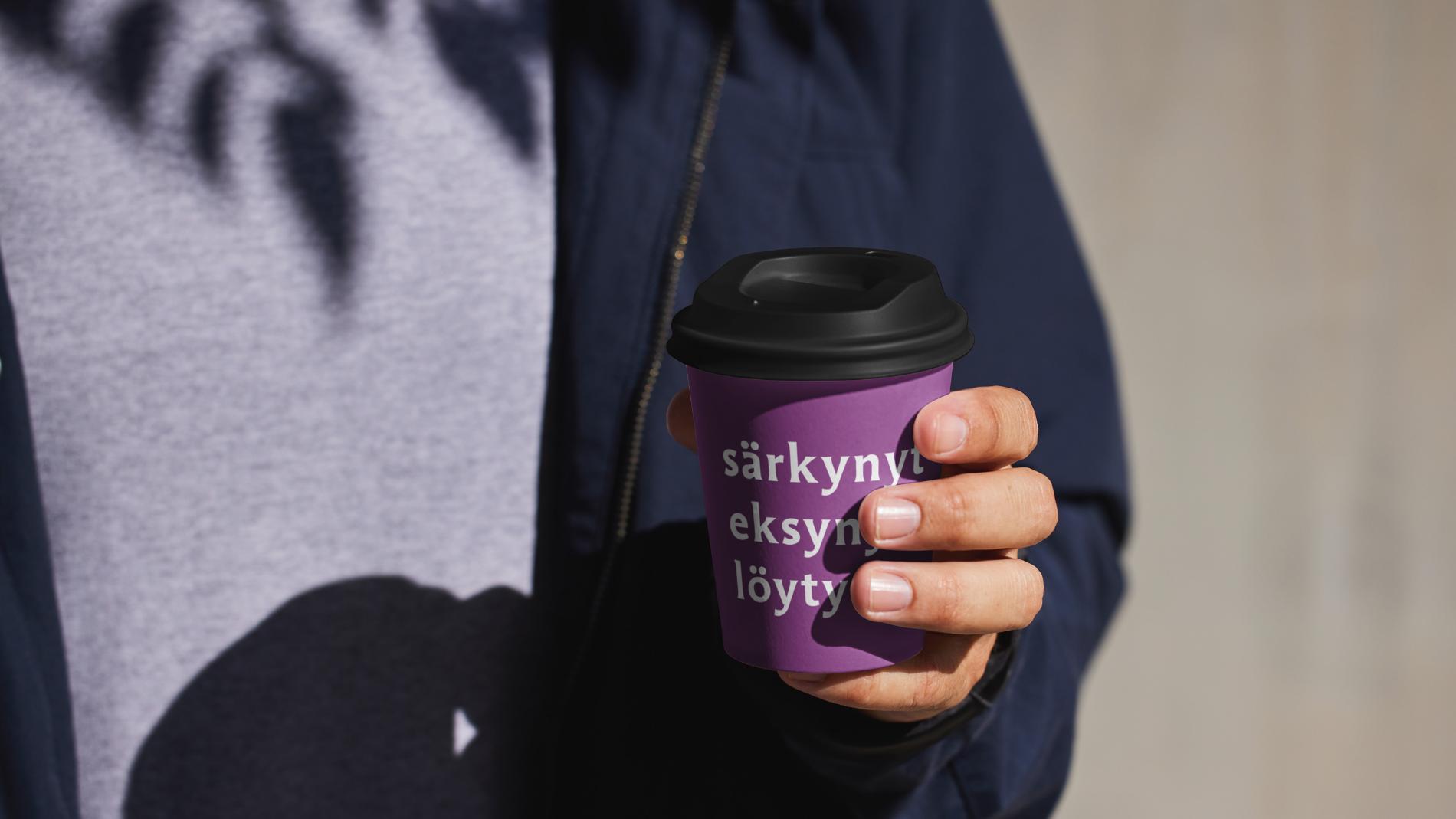 Henkilö pitää kädessään kahvimukia, jossa teksti särkynyt, eksynyt, löytynyt